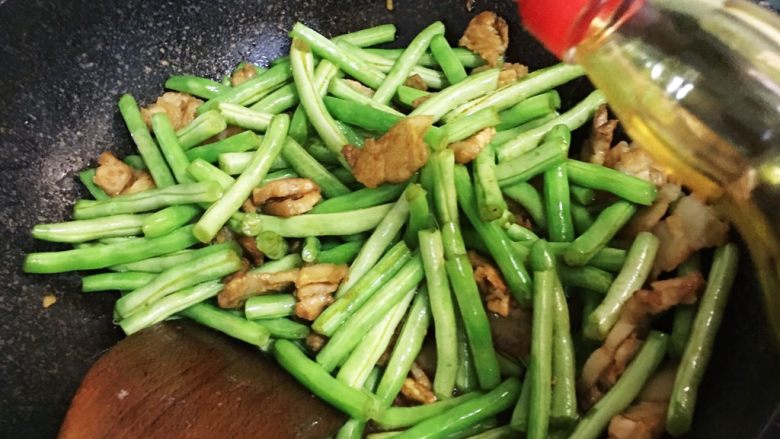 五花肉煸豆角,加入少许生抽,盖锅盖焖煮片刻。