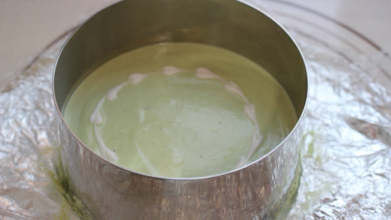 椰汁抹茶果冻慕斯,将步骤8的奶酪糊倒入准备好的慕斯圈中!轻磕几下震平!在慕斯糊表面滴几滴淡奶油,用牙签划一下,做出花纹