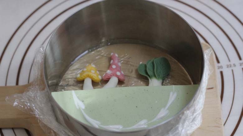 椰汁抹茶果冻慕斯,倒入一小部分糖水!糖水吉利丁冷冻至凝固以后,摆入做好的蘑菇和白菜!我还放了薄荷叶,然后倒入剩余的糖水吉利丁,和抹茶慕斯蛋糕一样平即可!冷冻至糖水吉利丁凝固!(这个过程大概30到40分钟就差不多,只要糖水吉利丁凝固即可,不可冷冻太长时间)
做好的蛋糕继续放冰箱冷藏室,冷藏过夜!吃的时候脱模即可!