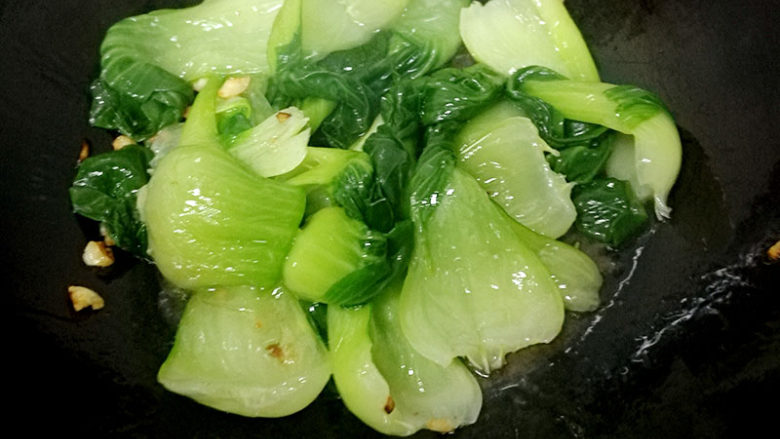 鲜香美味的香菇油菜教程,再起锅,等锅热后加入葵花籽油,再放入葱、蒜末,生抽炒香后,再放入油菜,翻炒几下,再把油菜在盘中摆出造型备用。