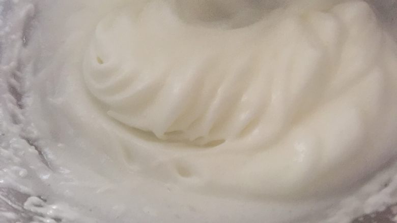 百香果溶豆,当纹路清晰时我们一次性倒入细砂糖，糖溶化混合均匀后，用干净的刮刀把边缘不均匀的蛋白霜刮到中间，然后转中速打发