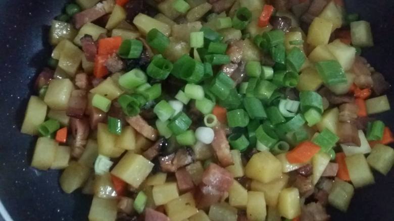 腊肉土豆焖饭,翻炒均匀后倒入葱花翻炒均匀关火。食材不用炒熟,因为还要放入锅中焖的。