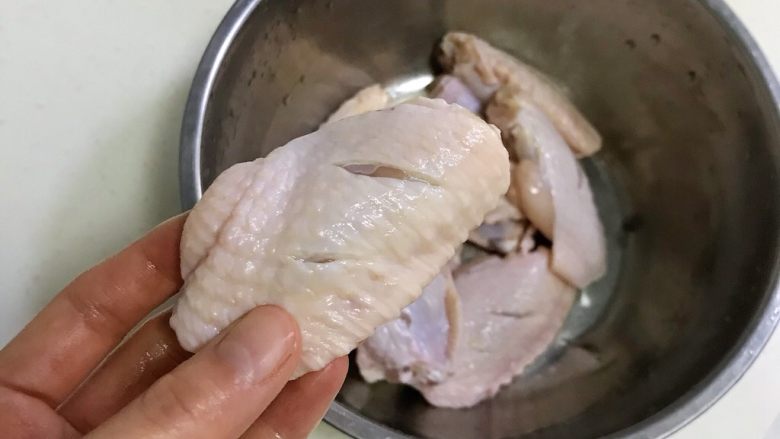 韩式吮指炸鸡翅,为了鸡翅更快更好的入味,用刀在鸡翅面上划2-3刀。