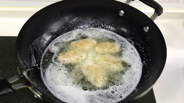 韩式吮指炸鸡翅,食用油加至7~8分热时,把鸡翅放入锅中转中火炸制,鸡翅放入锅时不要急于翻动,大约1~2分钟后再去翻动。