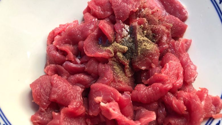 铁板牛肉,牛肉切好放入碗里,倒入少许油,放入1g黑胡椒粉