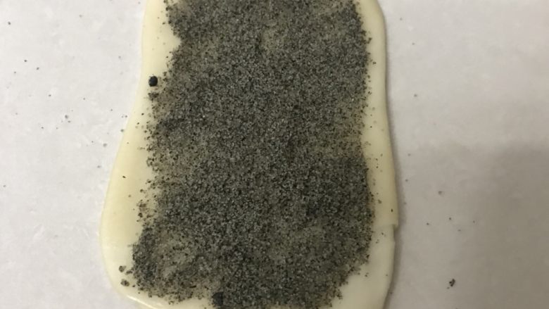 芝麻小脆饼,用擀面杖擀成稍长一点的面皮,表面撒上黑芝麻<a style='color:red;display:inline-block;' href='/shicai/ 869'>白砂糖</a>碎。