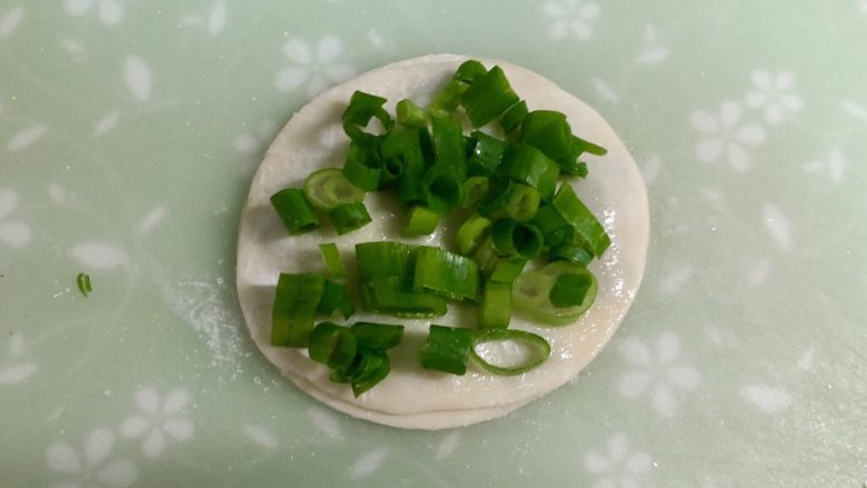 饺子皮葱油饼,撒上一些盐,铺上一层葱花。