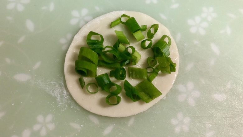 饺子皮葱油饼,撒上一些盐,铺上一层葱花。