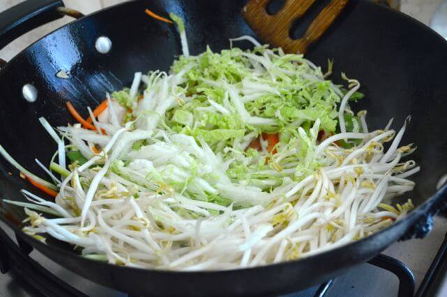 牛肉炒面,把所有的蔬菜都加到锅里。在高温下翻炒一分钟,然后在锅周围的圆周上加入一勺酒。