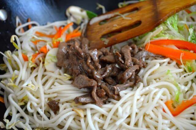 牛肉炒面,加牛肉,然后从底部搅拌30秒。 把锅盖上焖一分钟。开盖,加酱油、芝麻油、盐。搅拌均匀,再炒一分钟,起锅。