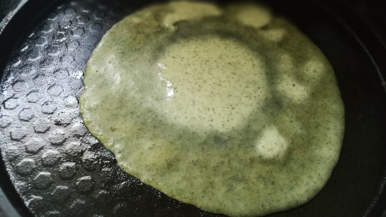 艾叶鸡蛋卷饼,倒入一勺艾叶面糊,摊成厚薄适中的圆形,煎成面饼