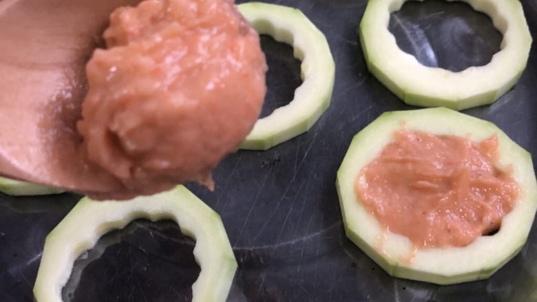 鲜虾西葫芦圈圈,西葫芦圈圈铺在提前抹一层薄油的盘子里(抹油主要是出锅放粘)用勺子挖取适量打好的虾泥放入西葫芦的中间,用勺背抹平表面