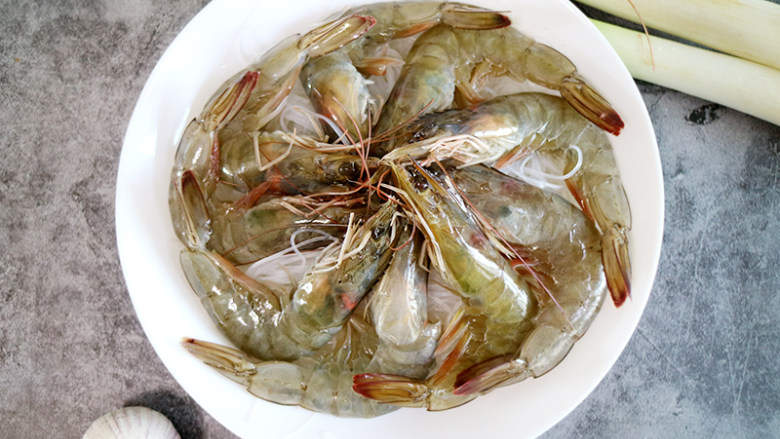 鲜美飘香的蒜蓉粉丝蒸虾,泡好的粉丝沥干水份剪短后铺在盘底,将虾一个个整齐地摆在粉丝上。