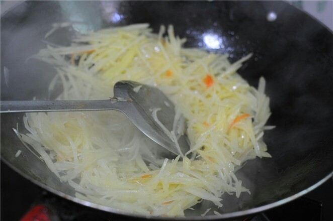 蒸饼卷菜,热锅烧油,将土豆丝炒至八成熟