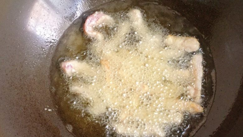 糖醋里脊,锅中倒入适量油烧至八成热,放入裹好粉的里脊肉条,中小火炸制(要一根一根的放)
