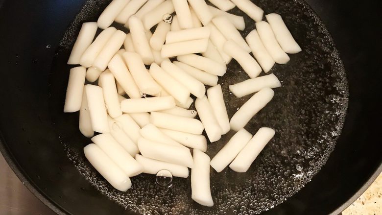 韩国辣酱炒年糕,锅内倒入适量清水煮沸,年糕入锅煮软