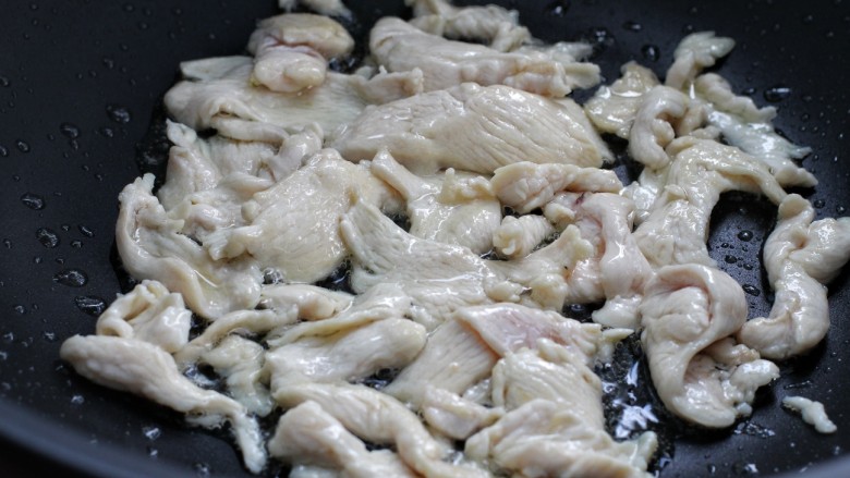 西芹火腿炒鸡片,锅中倒25克食用油油烧热后放入鸡片,翻炒至发白变色状态,盛出备用
