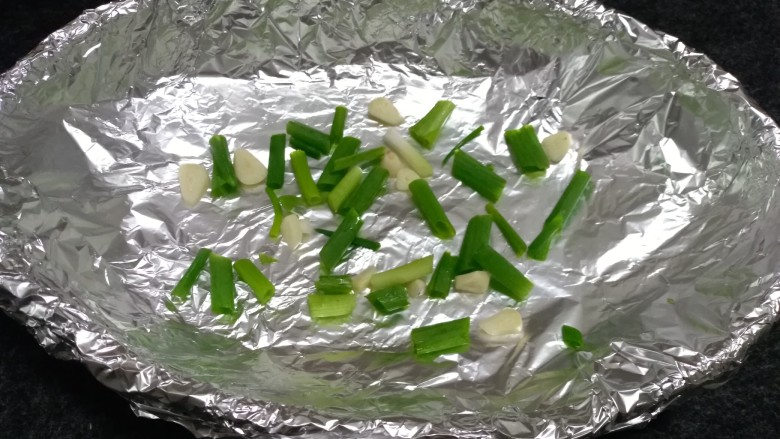 烤箱版烧烤南极冰鱼,烤盘用锡纸包裹好后,放入葱段,蒜片铺底