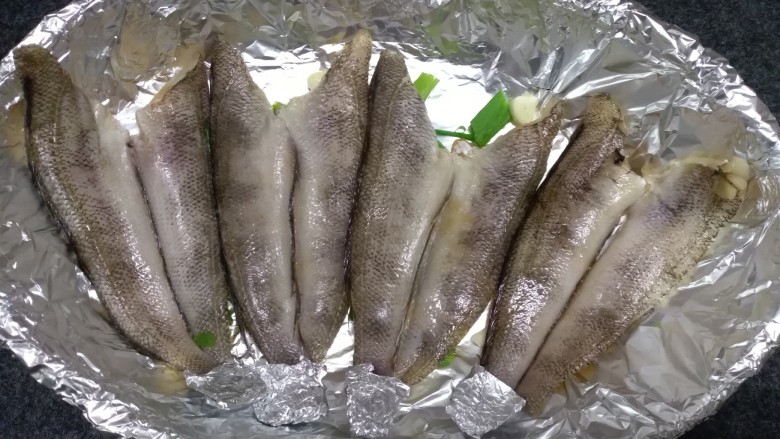 烤箱版烧烤南极冰鱼,放入腌制好的鱼,腌制的料不要。鱼尾用锡纸包裹住,因为烤至过程中容易糊。