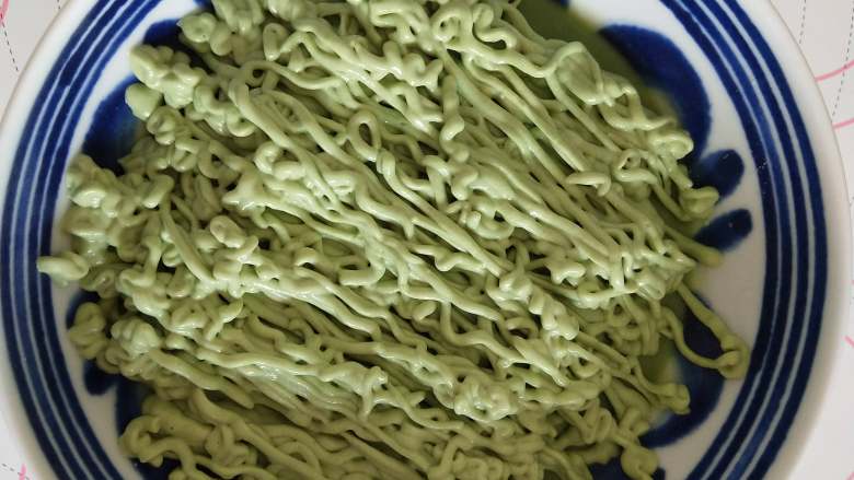 以假乱真的“菠菜面”,将冷藏好的抹茶豆腐糊装入裱花袋中(抹茶豆腐糊挤出来以后的线条状不会消失即可),将裱花袋中的抹茶豆腐挤入碗中,挤成面条状!将挤好面条的碗放冰箱冷冻一下