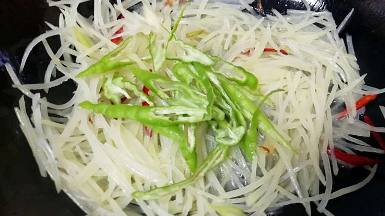 酸辣土豆丝,下入线辣椒丝,放盐翻炒均匀。