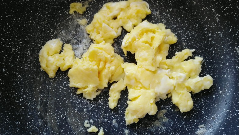 毛豆炒鸡蛋,鸡蛋翻炒凝固后,把鸡蛋倒入盘子。