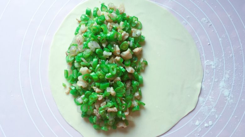 豆角饼,将馅料放在饼皮的二分之一处,边缘位置要留空(馅料尽量多放些,越多越好吃)。