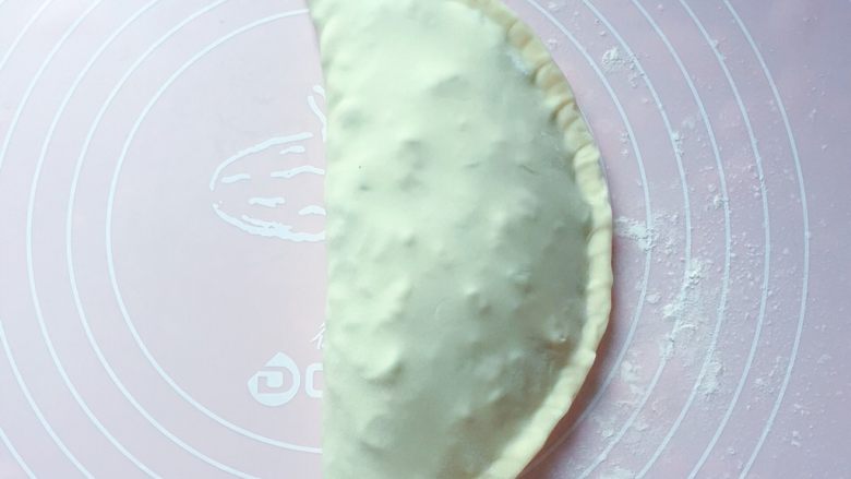 豆角饼,再将另一半饼皮掀起来覆盖到馅料上,边缘封口处用手捏紧,成为一个酷似牛角形的饼。
