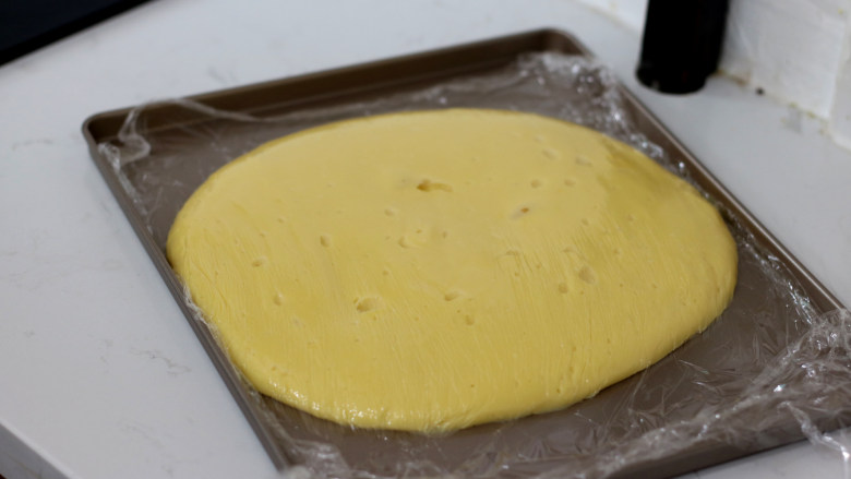低脂豆乳天使蛋糕卷,倒入不粘烤盘中,摊开后,保鲜膜贴面保存放凉备用。