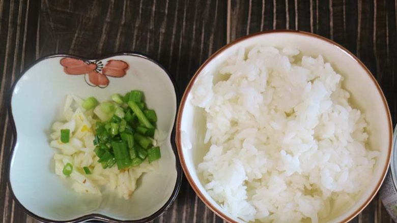 鲜香味美的金枪鱼炒饭,将隔夜米饭先在碗里弄散,小葱和大蒜用刀切碎装入容器中备用。