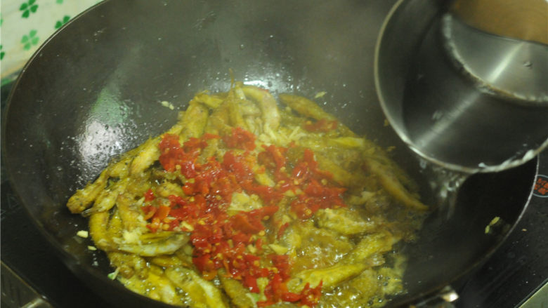 香酥小河鱼,沿着锅边淋入少许的水,转中大火,不用盖锅盖,用锅铲将鱼轻轻推动下,水分焖烧至稍微留点点汁