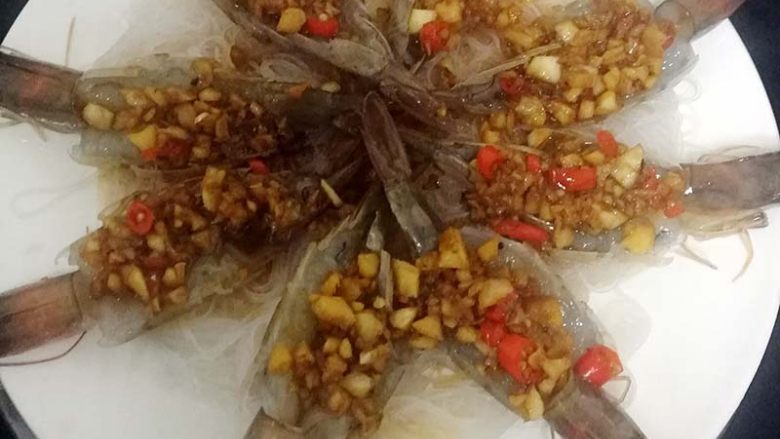 蓉粉丝开背虾,在用蒸锅,水开后,蒸制大约十分钟左右,然后把青红辣椒末散在粉丝上面,放一点酱油调味。