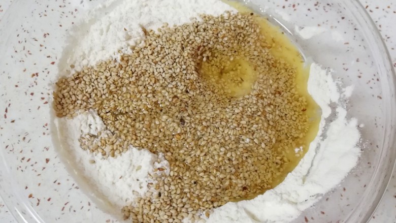 葱香爱心饼干,混合好的低筋面粉里面加入玉米油和白芝麻,用筷子搅拌均匀。
