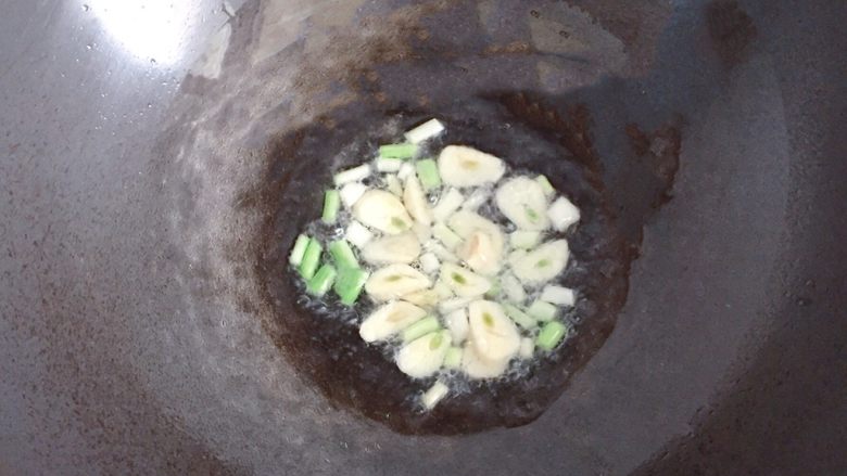 肉末炒豆角,锅中倒入少许油,放入葱白和蒜片爆香。