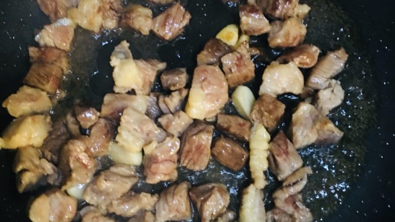 西红柿土豆炖牛腩,锅内放油,油八成熟后、放入蒜爆香,接着放入牛腩煸炒。