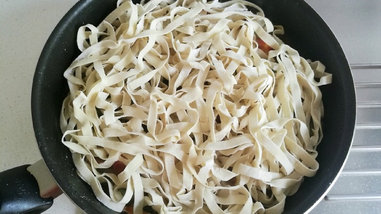 豆角番茄焖面,打开锅盖,将鲜面条均匀的铺在豆角上面。