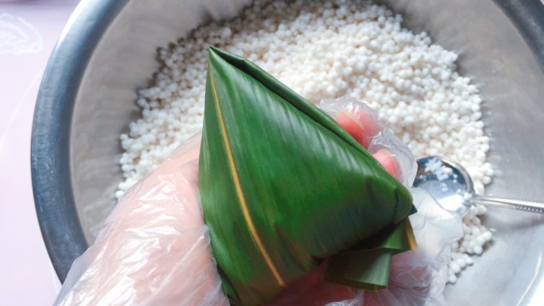 蜜枣西米粽子,顺着边边将粽叶折好;