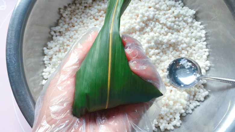 蜜枣西米粽子,再把粽叶上端的叶子向下折,直到完全盖住开口的地方就好了;