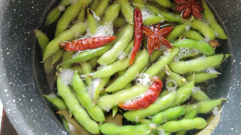 蒜泥毛豆,水煮沸后,放入提前准备好的食盐、八角、干辣椒,良姜、香叶,毛豆。