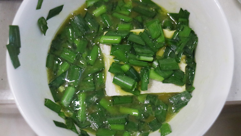 外酥里嫩的香煎豆腐,将装鸡蛋的碗中放入韭菜碎末继续搅拌,再将豆腐片放到韭菜鸡蛋液中。