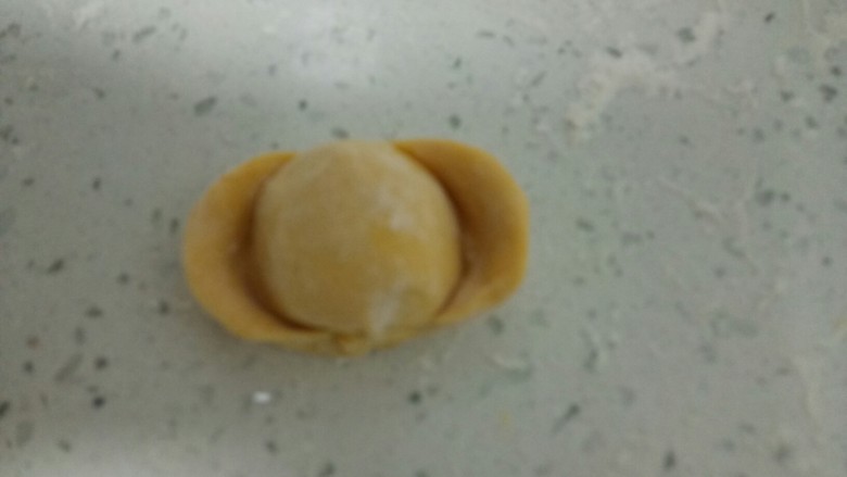 南瓜花样小馒头,取一个剂子,排气后,用手团圆,再搓成长条,两端约留1寸,用拇指在两端分别压扁,再从两端往中间推,两边捏紧。