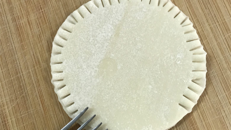 饺子皮版鸡蛋灌饼,然后用叉子把饺子皮四周用力按压,让两片饺子皮粘住。