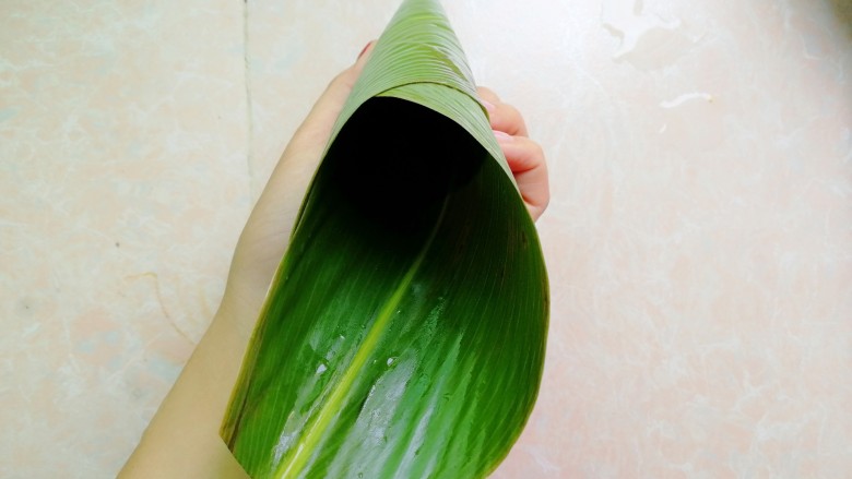 杂豆蜜枣小米粽,然后手捏住上面那一头粽叶转一圈,形成更长的牛角形状,看不懂的多看上图和此图的区别,就明白了