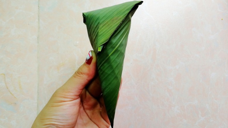 杂豆蜜枣小米粽,再把顶端的往下折,如图,然后用粽绳绑起来
