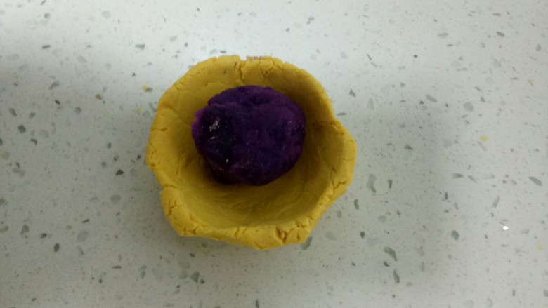 两种口味的糯米南瓜饼,取一个小剂子用拇指按压成碗状,包入紫薯馅。