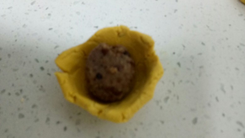 两种口味的糯米南瓜饼,去一个小剂子,用拇指按压成碗状,放入豆沙馅。