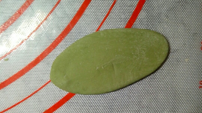 萌粽豆沙包,取约6克一个的绿色面团,搓成两头尖的锥形,再用刮板压扁。