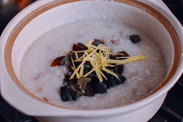 皮蛋瘦肉粥,加入姜丝、猪肉和<a style='color:red;display:inline-block;' href='/shicai/ 14'>皮蛋</a>。继续搅拌煨5分钟左右。最后,加入白胡椒和盐调味。