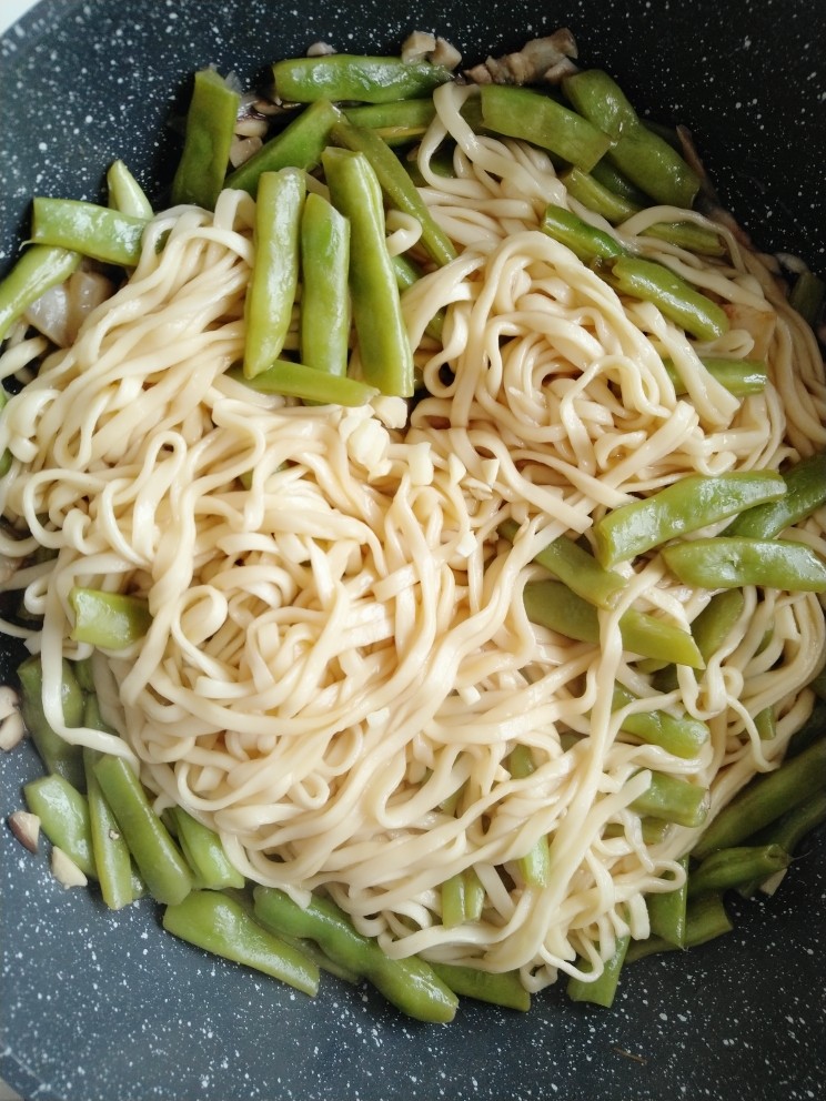 豆角焖面,再次冒气后,大火收汁,倒入剩下的蒜瓣,关火盖上锅盖焖至一分钟(一定要确认面条基本熟后在关火焖至一分钟)。