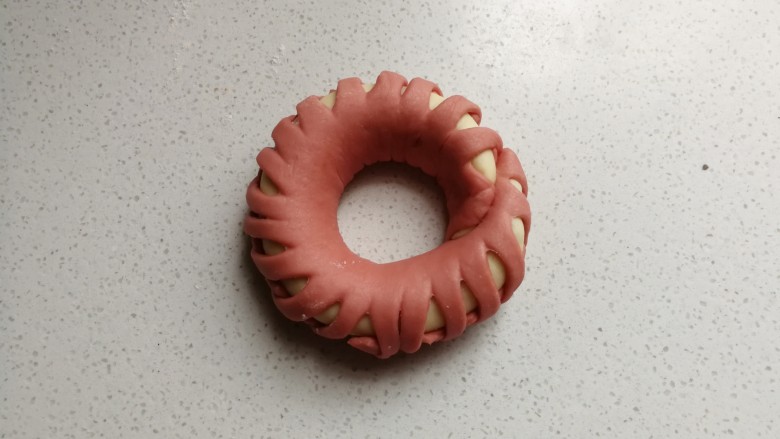 花环豆沙包,编好后围成圆环,首尾处沾点水粘起来,然后摆入烤盘中,再继续做完剩下的三个花环包,然后都摆入烤盘中进行发酵。